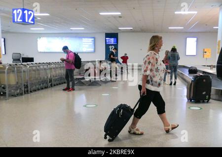 Passeggeri visti con le maschere facciali obbligatorie all'aeroporto internazionale ATH LGAV di Atene, in Grecia, il 18 giugno 2020, dopo la quarantena di Coronavirus e le restrizioni di viaggio. I passeggeri che indossano maschere e guanti, utilizzano disinfettanti per le mani come misura preventiva contro la diffusione della pandemia COVID-19. La Grecia e l'Europa hanno chiuso a lungo le frontiere per le persone al di fuori dell'Europa e della zona Schengen, ma la Grecia ha iniziato a revocare il divieto di circolazione dal 15 giugno 2020 per i paesi della zona Schengen e il 1 luglio 2020 si arriverà a un maggiore allentamento. I passeggeri in arrivo sono soggetti al decor Foto Stock