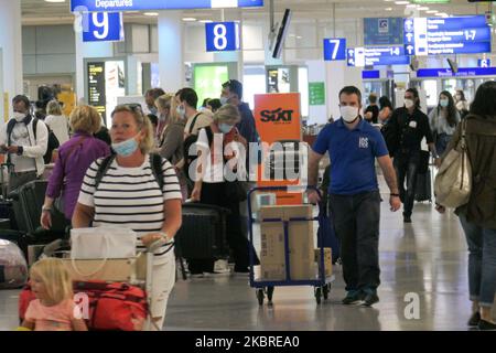 Passeggeri visti con le maschere facciali obbligatorie all'aeroporto internazionale ATH LGAV di Atene, in Grecia, il 18 giugno 2020, dopo la quarantena di Coronavirus e le restrizioni di viaggio. I passeggeri che indossano maschere e guanti, utilizzano disinfettanti per le mani come misura preventiva contro la diffusione della pandemia COVID-19. La Grecia e l'Europa hanno chiuso a lungo le frontiere per le persone al di fuori dell'Europa e della zona Schengen, ma la Grecia ha iniziato a revocare il divieto di circolazione dal 15 giugno 2020 per i paesi della zona Schengen e il 1 luglio 2020 si arriverà a un maggiore allentamento. I passeggeri in arrivo sono soggetti al decor Foto Stock