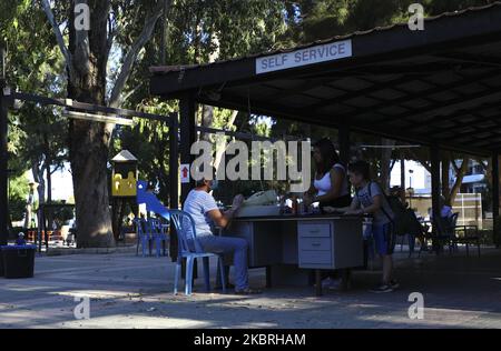 Un cassiere in una maschera protettiva serve i clienti in una caffetteria nel parco. Limassol, Cipro, Martedì, Giugno 23, 2020 il Ministero della Salute di Cipro dal Giugno 24 abroga la regola che limita le riunioni ad un massimo di 10 persone. Così, dal giugno 24, il numero massimo consentito di partecipanti alle riunioni in sale chiuse è di 75 persone, per sale aperte - 150 persone. Questa regola si applica alle cerimonie nuziali, ai battesimi, ai concerti, alle feste, alle riunioni private nelle case (in questo caso, i proprietari della casa sono considerati anche partecipanti) e a tutte le altre forme di riunioni di massa. Più grande e più numerou Foto Stock