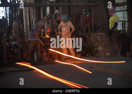 Bangladesi ancora lavoratori di ri-laminatoio visto lavorare nel acciaio ri-laminatoio a Narayanganj, periferia di Dhaka, Bangladesh il 27 giugno 2020. In questi mulini il ferro è forgiato in 1200 + a 1300+ Celsius. In un luogo così riscaldato, è probabile che le suole delle scarpe vengano bruciate con un passo incauto. (Foto di Ahmed Salahuddin/NurPhoto) Foto Stock