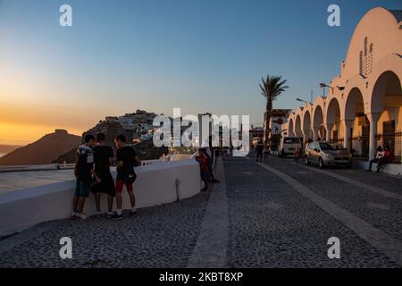 Tourists and locals are gathering to watch the sunset. Sunset view from Thera in Santorini island, Cyclades in the Aegean Sea in Greece. A few tourists and locals enjoy the magical sunset over the volcano in Fira as the country opened the airports and allowed tourists to come after July 1 because of the coronavirus Covid-19 pandemic general lockdown measures that started easing since June 15. Greece recently reopened the tourism summer season with the prime minister Kyriakos Mitsotakis having a speech from Santorini during the sunset to relaunch the touristic season as the Greek economy is hea Stock Photo