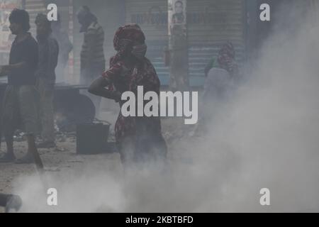 Una donna attende che il bitume e le miscele rocciose siano utilizzate per riparare una strada a Dhaka, Bangladesh, il 10 luglio 2020. (Foto di Ahmed Salahuddin/NurPhoto) Foto Stock