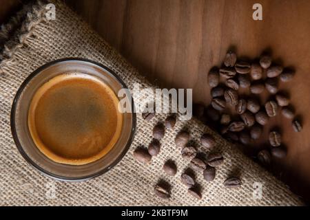 Chicchi di caffè arrosto con espresso in tazza di vetro, vista dall'alto Foto Stock