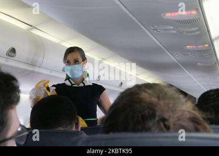 Equipaggio di cabina con maschera facciale che mostra la dimostrazione della sicurezza. Volo su un velivolo turboprop Olympic Air De Havilland Canada DHC-8-400 durante l'era pandemica del Coronavirus Covid-19 con uso obbligatorio di maschere facciali per i passeggeri. L'equipaggio di volo, la donna che si occupa della gestione dell'aria, indossa anche attrezzature di sicurezza come maschere facciali e guanti mentre i pasti vengono cambiati e viene fornito un tovagliolo disinfettante. La tratta di volo nazionale è dall'aeroporto ATH LGAV di Atene, la capitale greca, alle isole delle Cicladi. Greci e stranieri viaggiano verso famose isole come Mykonos o Santorini dopo il greco Foto Stock