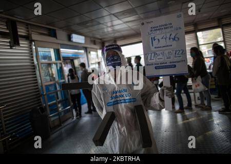 Un dipendente che indossa indumenti protettivi come precauzione contro il nuovo coronavirus tiene un banner che mostra informazioni sul virus e su quelli infetti presso la stazione centrale degli autobus Harmoni di Giacarta, Indonesia, il 17 luglio 2020. L’Indonesia ha il numero più alto di infezioni da coronavirus e di decessi nel sud-est asiatico. Secondo il funzionario del ministero della sanità, nelle ultime 24 ore nove province hanno registrato un numero elevato di casi. il presidente indonesiano, Joko Widodo, ha invitato il pubblico ad obbedire ai protocolli sanitari attuati per evitare ulteriori infezioni da COVID-19. (Foto di Afriadi Hi Foto Stock