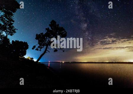 La Via Lattea, parte della nostra Galassia dove il nostro sistema solare appartiene come visto il 17 luglio 2020 dalla spiaggia di Epanomi vicino a Salonicco e Chalkidiki in Grecia durante la notte dopo la mezzanotte nel cielo estivo buio greco sulle calme acque mediterranee del Mar Egeo, la spiaggia di sabbia e i pini selvatici. La Via Lattea è una galassia a spirale con una stima che contiene 100-400 miliardi di stelle e pianeti. (Foto di Nicolas Economou/NurPhoto) Foto Stock