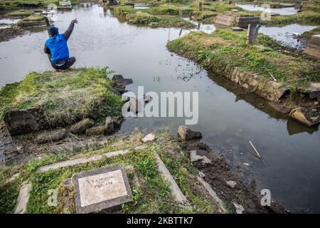 Una vista del cimitero pubblico che sommerse dalle acque di alluvione dall'aumento del livello del mare il 18 luglio 2020 a Giacarta Nord, Indonesia. Dagli anni '1970s, alcune parti di Giacarta sono affondate per più di quattro metri, ad una velocità fino a 25 centimetri l'anno. La capitale indonesiana di Giacarta ospita 10 milioni di persone, ma è anche una delle città più affondate al mondo. Circa il 40% di Giacarta si trova sotto il livello del mare. (Foto di Afriadi Hikmal/NurPhoto) Foto Stock