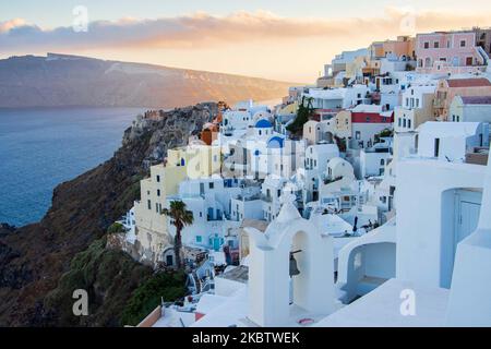 Vista panoramica del bellissimo paesaggio pittoresco della città di Oia, Grecia, il 6 luglio 2020 durante l'ora magica, il tramonto del tramonto e le chiese a cupola blu. Case o alberghi con la famosa architettura tradizionale delle isole Cicladi sulla Caldera del vulcano e il Mar Egeo. L'isola di Santorini e' una delle piu' famose destinazioni greche e mediterranee, famosa per il vulcano attivo e il tramonto, e' considerata una destinazione romantica e rilassante per le vacanze estive e la luna di miele. Durante il tramonto, ci sono di solito migliaia di coppie, turisti da tutto il mondo Foto Stock