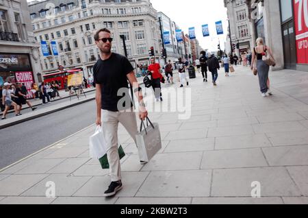 A man carries bags of shopping along Oxford Street in London, England, on July 22, 2020. UK retail sales data for June, during which non-essential shops were allowed to reopen, is set to be released by the Office for National Statistics (ONS) this Friday, July 24. The day will also be the first that people in England will be required to wear face masks or other kinds of face covering in shops and supermarkets. Face coverings on public transport have been compulsory across England since mid-June. (Photo by David Cliff/NurPhoto) Stock Photo