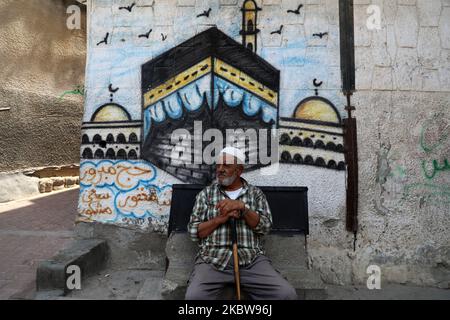 Un uomo palestinese si siede di fronte a un murale della sacra Kaaba, a Gaza City, 27 luglio 2020.la stagione hajj 2020, che è stata ridotta drammaticamente per includere solo circa 1.000 pellegrini musulmani come l'Arabia Saudita batte un aumento di coronavirus, è destinato a iniziare il 29 luglio. Circa 2,5 milioni di persone provenienti da tutto il mondo di solito partecipano al rituale che si svolge in diversi giorni, incentrato sulla città Santa della Mecca. L'hajj di quest'anno si terrà in base a rigorosi protocolli igienici, con accesso limitato ai pellegrini sotto i 65 anni e senza alcuna malattia cronica. (Foto di Majdi Fathi Foto Stock