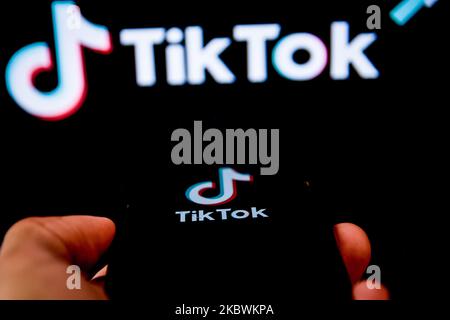 Logo TikTok closeup visualizzato sullo schermo di uno smartphone e un altro logo TikTok come sfondo su uno schermo TV a Chania, Isola di Creta, Grecia il 3 agosto 2020. Il presidente degli Stati Uniti Donald Trump sta minacciando e pianificando di vietare la popolare applicazione di condivisione video TikTok dagli Stati Uniti a causa del rischio per la sicurezza. (Foto di Nikolas Kokovlis/NurPhoto) Foto Stock