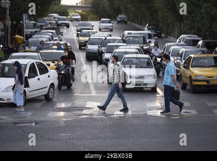 Gli uomini iraniani che indossano maschere protettive attraversano un viale nel nord di Teheran, in Iran, il 9 agosto 2020 a seguito della nuova epidemia di coronavirus (COVID-19) in Iran. (Foto di Morteza Nikoubazl/NurPhoto) Foto Stock