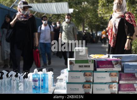 Gli iraniani che indossano maschere protettive passano accanto a bottiglie di liquido disinfettante e confezioni di maschere protettive che vengono esposte su una strada da un venditore nel nord di Teheran, Iran, il 9 agosto 2020 a seguito della nuova epidemia di coronavirus (COVID-19) in Iran. (Foto di Morteza Nikoubazl/NurPhoto) Foto Stock