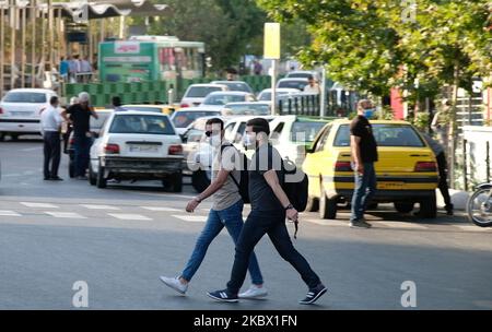 Due uomini iraniani che indossano maschere protettive attraversano un viale nel nord di Teheran, a seguito della nuova epidemia di coronavirus (COVID-19) in Iran, il 9 agosto 2020. (Foto di Morteza Nikoubazl/NurPhoto) Foto Stock