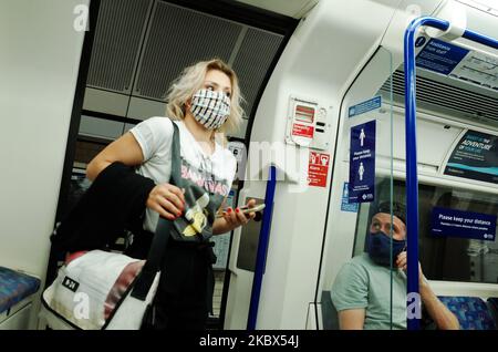 Una donna che indossa una maschera facciale, attualmente incaricata dei trasporti pubblici, sale a un servizio di metropolitana della Northern line alla stazione di Warren Street a Londra, Inghilterra, il 14 agosto 2020. Il numero di passeggeri della metropolitana di Londra rimane ben al di sotto dei livelli pre-pandemici, mentre la città continua la sua esitazione dal blocco del coronavirus, con i timori del covid-19 che ancora oggi molti non utilizzano i trasporti pubblici. (Foto di David Cliff/NurPhoto) Foto Stock