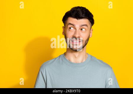 Ritratto foto di giovane divertente nervoso eccitato bearded uomo morso labbra oops spiacente errore operaio non guardare vuoto spazio annuncio isolato sul colore giallo Foto Stock