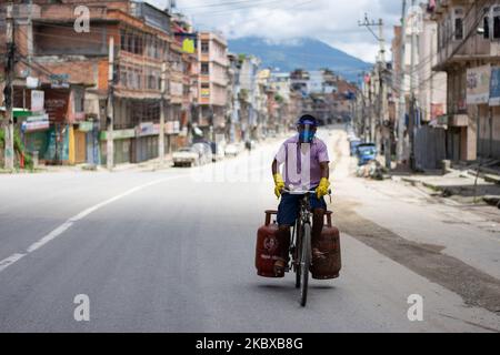 Un uomo di consegna di bombole di gas che indossa uno scudo facciale cavalca su una strada deserta dopo che il governo ha riimposto il blocco per una settimana come misura preventiva contro la diffusione del coronavirus COVID-19 a Kathmandu, Nepal il 20 agosto 2020. (Foto di Rojan Shrestha/NurPhoto) Foto Stock