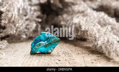 Minerale di fillosilicato Chrysocolla colorato in ciano tumbled su sfondo di legno Foto Stock