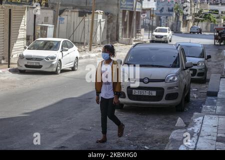 Una ragazza palestinese che indossa una maschera protettiva durante le passeggiate per strada a Gaza City, il 25 agosto 2020. È stato imposto un blocco totale alla striscia di Gaza assediata dopo che le autorità hanno confermato i primi casi di coronavirus diffusi nella comunità, sollevando i timori di un'epidemia potenzialmente devastante nel territorio palestinese impoverito, lunedì, Il ministero della sanità ha dichiarato che quattro persone della stessa famiglia sono state giudicate positive nel centro di Gaza e Un blocco di 48 ore è entrato in vigore il lunedì sera in tutto il territorio, compreso il campo profughi al-Magasi, dove la famiglia vive. Foto Stock