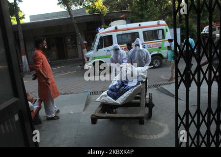 Gli operatori sanitari che indossano i dispositivi di protezione individuale (PPE) spingono un carrello a mano che trasporta il corpo di una persona morta a causa del coronavirus COVID-19 prima della cremazione in una fornace presso il Nigambodh Ghat Cremation Ground, a Nuova Delhi, India, il 26 agosto 2020. (Foto di Mayank Makhija/NurPhoto) Foto Stock