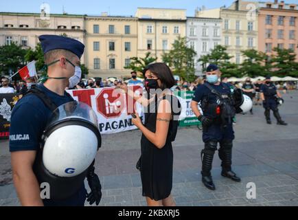 Un attivista pro-LGBT in discussione con un ufficiale di polizia di fronte ai membri delle organizzazioni nazionaliste di estrema destra e gli attivisti pro-vita visti durante una contro protesta, contro LGBT e la marcia di uguaglianza. L'edizione di quest'anno della marcia per l'uguaglianza è stata modificata in un formato diverso a causa delle misure imposte dal governo e dalla zona "Stato giallo" per la città di Cracovia imposte dal Ministero della Salute solo un paio di giorni fa. La marcia annuale si è svolta intorno alla piazza principale. Sabato 29 agosto 2020, a Cracovia, Malopolskie Voivodato, Polonia. (Foto di Artur Widak/NurP Foto Stock