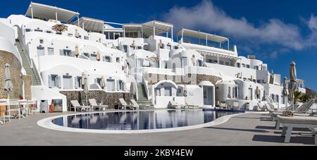 Piscina in un hotel resort a 5 stelle con sedie a sdraio e asciugamano che si affaccia su una splendida vista sulla Caldera sul mare Egeo con tradizionale architettura a terrazze greca a calce e mediterranea di case e resort. Isola di Santorini nelle Cicladi, Grecia durante una calda giornata estiva di sole. Santorini è di solito sovraffollata in quanto è famosa per il suo tramonto, che attrae soprattutto coppie da tutto il mondo per la magica vista del tramonto sul vulcano, Ma quest'anno a causa della pandemia di Coronavirus Covid-19 ci sono meno arrivi del solito, riducendo anche il reddito del PIL del conteggio Foto Stock