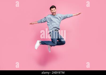 Foto a grandezza naturale di giovane attraente bello divertente pazzo studente ragazzo salto aria ali palme libertà positiva spensierato isolato su colore rosa pastello Foto Stock