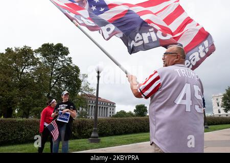 Randal Thom, partecipante di marzo, sventola una bandiera Trump sovradimensionata mentre altri guardano. Settembre 12, 2020. Un gruppo di circa 200 sostenitori di Trump - molti dei quali armati - ha marciato nella capitale dello Stato del Minnesota a St. Paul, Minnesota, dove hanno tenuto un raduno di tre ore. Gli oratori hanno condannato i politici democratici e il movimento Black Lives Matter, criticato la risposta del governatore Tim Walz alla pandemia COVID-19, negato l'esistenza di razzismo, e sostenuto la rielezione di Donald Trump. Mentre i marchers hanno fatto il loro senso alla capitale, un gruppo dei contro manifestanti ha confrontato i partecipanti. Gli ufficiali della Patrol di Stato hanno diviso il Foto Stock