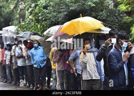 I nepalesi e i lavoratori migranti indiani insieme ad un rivestimento ombrello per il test PCR all'esterno al Sukraraj Tropical & Infectious Disease Hospital, Teku, Kathmandu, Nepal il 24 settembre 2020. (Foto di Narayan Maharjan/NurPhoto) Foto Stock