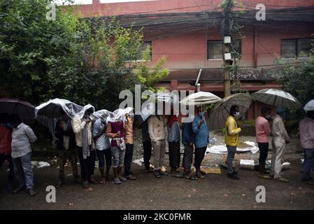 I nepalesi e i lavoratori migranti indiani insieme ad un rivestimento ombrello per il test PCR all'esterno al Sukraraj Tropical & Infectious Disease Hospital, Teku, Kathmandu, Nepal il 24 settembre 2020. (Foto di Narayan Maharjan/NurPhoto) Foto Stock