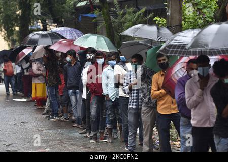 I nepalesi e i lavoratori migranti indiani insieme ad un rivestimento ombrello per il test PCR all'esterno al Sukraraj Tropical & Infectious Disease Hospital, Teku, Kathmandu, Nepal il 24 settembre 2020. (Foto di Narayan Maharjan/NurPhoto) Foto Stock