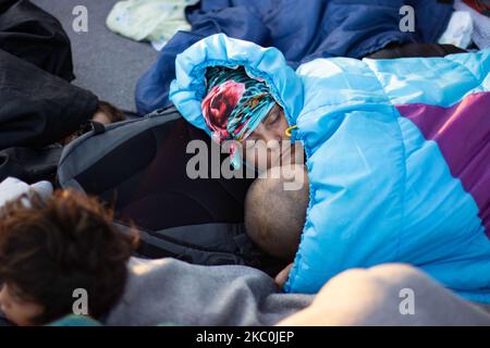 Una madre afghana che dorme con qui un bambino in viaggio. La mattina presto, con più di 10,000 richiedenti asilo che dormono lungo la strada dopo l'incendio nel campo profughi di Moria, il centro di identificazione e registrazione. Rifugiati senza tetto e migranti senza alcun rifugio o strutture come servizi igienici o acqua corrente vivono sulla strada tra Mytilene o Mitlini città, la capitale dell'isola e Moria, vicino a Karatepe, con conseguente chiusura della strada principale dell'isola, Nelle tende di fortuna, come non c'era posto per ospitarle in quel momento, più tardi il nuovo temporaneo Kara Tepe o Mavrovouni Refugee c Foto Stock