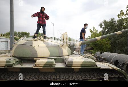 Un uomo iraniano e una donna sono in piedi su un carro armato militare mentre visitano il Giardino-Museo della Santa difesa durante una mostra di guerra per commemorare l'anniversario della guerra Iran-Iraq (1980-88), a Teheran il 29 settembre 2020. (Foto di Morteza Nikoubazl/NurPhoto) Foto Stock