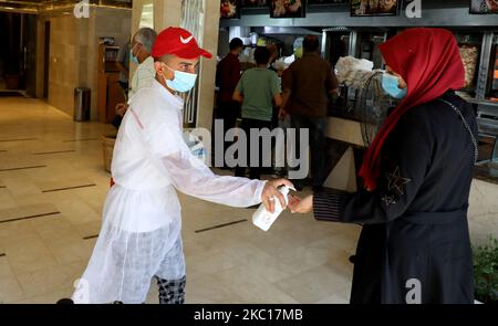 Una donna che indossa una maschera protettiva riceve gel antisettico da un personale di un ristorante in mezzo al coronavirus COVID-19 pandemico in corso Khan Yunis nella striscia di Gaza meridionale il 5 ottobre 2020. (Foto di Majdi Fathi/NurPhoto) Foto Stock