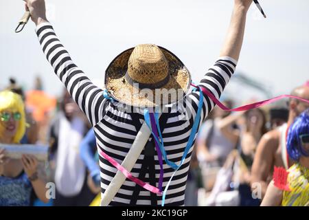 Una persona in un cappello di vimini con le mani in su durante un festival Foto Stock