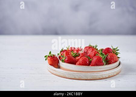 Fragole fresche in due piatti di ceramica leggera su un tavolo di legno bianco. Orizzontale, spazio di copia, primo piano. Foto Stock