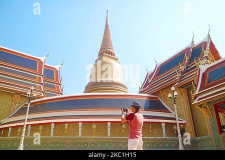 I visitatori scattano foto nel cortile del tempio buddista Wat Ratchabophit con la gigantesca Pagoda dorata e il chiostro circolare, Bangkok, Thailandia Foto Stock