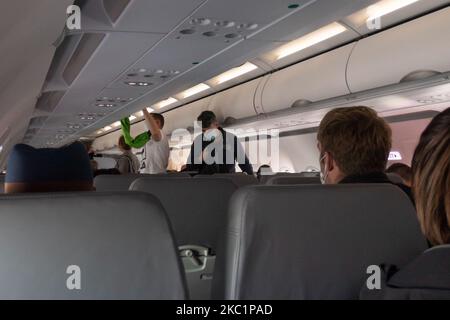 Passeggeri con maschere facciali durante l'imbarco in cabina. Volo con Lauda Airbus A320 aereo con registrazione 9H-LMJ durante la pandemia di Coronavirus Covid-19 con passeggeri e equipaggio che indossano il facemask. Laudamotion o Lauda è un vettore austriaco a basso costo, di proprietà di Ryanair, che opera con i codici Ryanair FR per IATA, RYR per ICAO e RYANAIR. La compagnia aerea economica ha sede a Vienna International Airport vie LOWW o Flughafen Wien-Schwechat in Austria con una flotta di 28 aeromobili Airbus. Vienna, Austria il 12 ottobre 2020 (Foto di Nicolas Economou/NurPhoto) Foto Stock