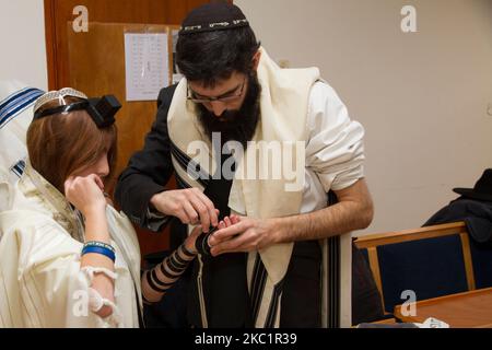 TEL AVIV, ISRAELE - 19 GENNAIO 2018: Un uomo ortodosso, indossando uno scialle di preghiera, ha messo un tefillin ebraico su Un braccio di un giovane uomo che si prepara alla preghiera, come parte di un Foto Stock