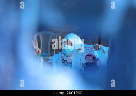 Una donna che indossa una maschera protettiva conserva un'immagine di Maher al-Akhras, 49, un palestinese incarcerato da Israele, che è in sciopero della fame per 80 giorni, protestando contro la sua detenzione senza processo, durante una protesta di solidarietà con al-Akhras e altri prigionieri, a Gaza City il 14 ottobre 2020. (Foto di Majdi Fathi/NurPhoto) Foto Stock