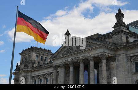 Bandiera tedesca sotto il cielo soleggiato di fronte al 'Reichstag' con la scritta 'al popolo tedesco' Foto Stock