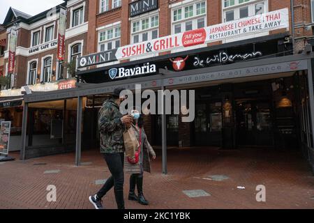 La gente di Eindhoven passa davanti a caffè e bar chiusi durante il blocco parziale e la vita quotidiana nella città di Eindhoven nei Paesi Bassi con persone che indossano il facemask come fuori a piedi o in bicicletta come misura protettiva contro la diffusione della pandemia di Coronavirus Covid-19. Martedì 13 ottobre 2020 il primo ministro olandese Mark Rutte ha annunciato che i Paesi Bassi devono tornare a un parziale blocco, chiudendo i bar, caffè e ristoranti, l'uso obbligatorio di maschera facciale al chiuso, la limitazione al numero di persone che si riuniscono al chiuso, le attività sportive e altro sono anche un Foto Stock