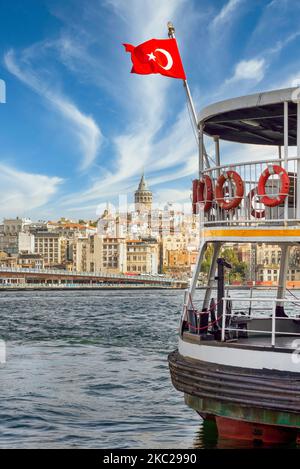 Bandiera turca su un traghetto, ormeggiata al terminal dei traghetti di Eminonu, lo stretto di Bosforo, con lo skyline della città di Istanbul, Turchia, sullo sfondo, tra cui la Torre Galata e il Ponte Galata Foto Stock