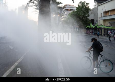 Un ciclista è colpito dal cannone d'acqua della polizia durante una protesta contro il presidente cileno Sebastian Pinera a Santiago il 23 ottobre 2020, in vista del referendum di domenica. (Foto di Matias Basualdo/NurPhoto) Foto Stock