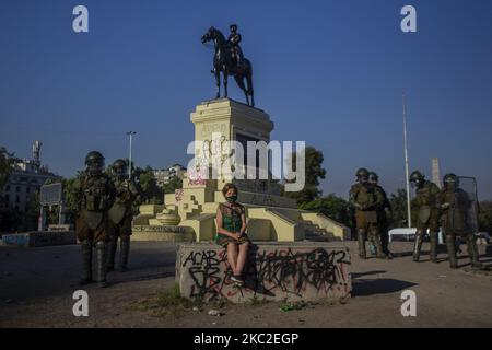 Una donna anziana adulta siede nel centro di Plaza Dignidad (ex plaza Italia), mentre viene molestata e intimidita dalla polizia tumultuosa dei carabineros del Cile, per ritirarsi dallo spazio pubblico durante una protesta contro il presidente cileno Sebastian Pinera a Santiago il 23 ottobre 2020, in vista del referendum di domenica. (Foto di Claudio Abarca Sandoval/NurPhoto) Foto Stock