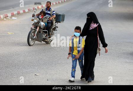 Una donna palestinese cammina accanto al suo bambino, nella città di Rafah, nella striscia di Gaza meridionale, il 24 ottobre 2020. (Foto di Majdi Fathi/NurPhoto) Foto Stock