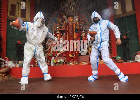 I devoti indù che indossano indumenti protettivi personali eseguono Dhunuchi, una danza tradizionale, di fronte a un idolo della dea Indù Durga durante il Durga Puja Festival presso la comunità Puja Pandal in mezzo alla pandemia COVID-19 a Kolkata, in India, il 25 ottobre 2020. (Foto di Debajyoti Chakraborty/NurPhoto) Foto Stock