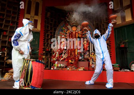 I devoti indù che indossano indumenti protettivi personali eseguono Dhunuchi, una danza tradizionale, di fronte a un idolo della dea Indù Durga durante il Durga Puja Festival presso la comunità Puja Pandal in mezzo alla pandemia COVID-19 a Kolkata, in India, il 25 ottobre 2020. (Foto di Debajyoti Chakraborty/NurPhoto) Foto Stock