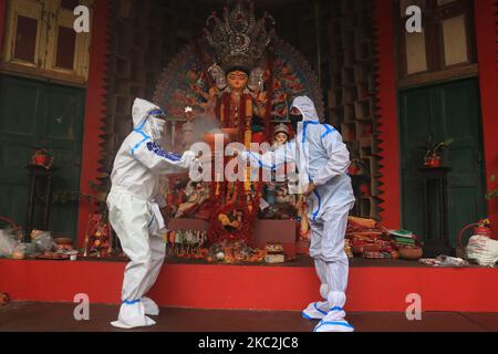 I devoti indù che indossano indumenti protettivi personali eseguono Dhunuchi, una danza tradizionale, di fronte a un idolo della dea Indù Durga durante il Durga Puja Festival presso la comunità Puja Pandal in mezzo alla pandemia COVID-19 a Kolkata, in India, il 25 ottobre 2020. (Foto di Debajyoti Chakraborty/NurPhoto) Foto Stock