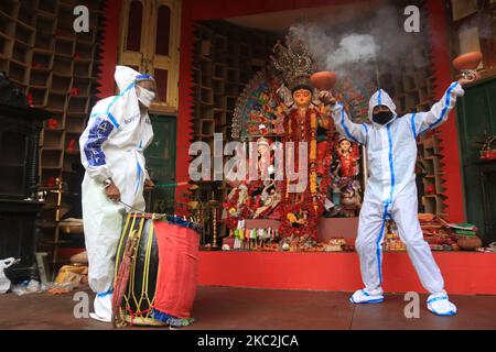 I devoti indù che indossano indumenti protettivi personali eseguono Dhunuchi, una danza tradizionale, di fronte a un idolo della dea Indù Durga durante il Durga Puja Festival presso la comunità Puja Pandal in mezzo alla pandemia COVID-19 a Kolkata, in India, il 25 ottobre 2020. (Foto di Debajyoti Chakraborty/NurPhoto) Foto Stock